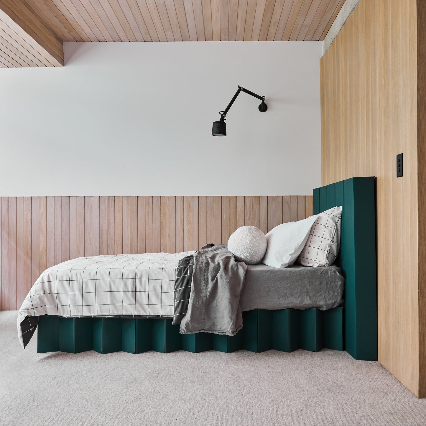 Side view of the assembled Yona forest green bed base with headboard