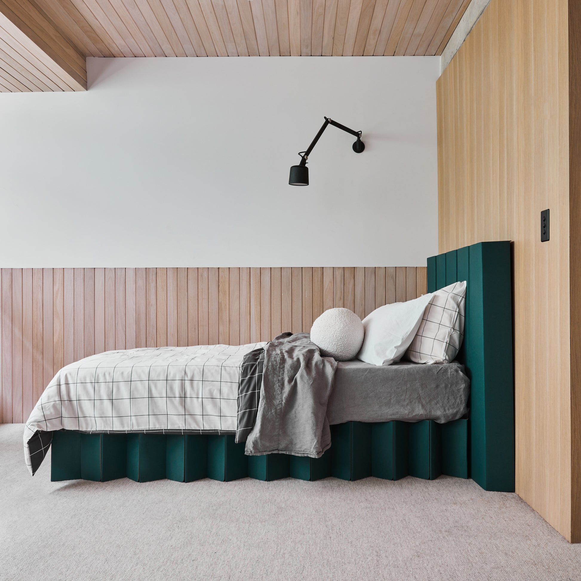 Side view of the assembled Yona forest green bed base with headboard