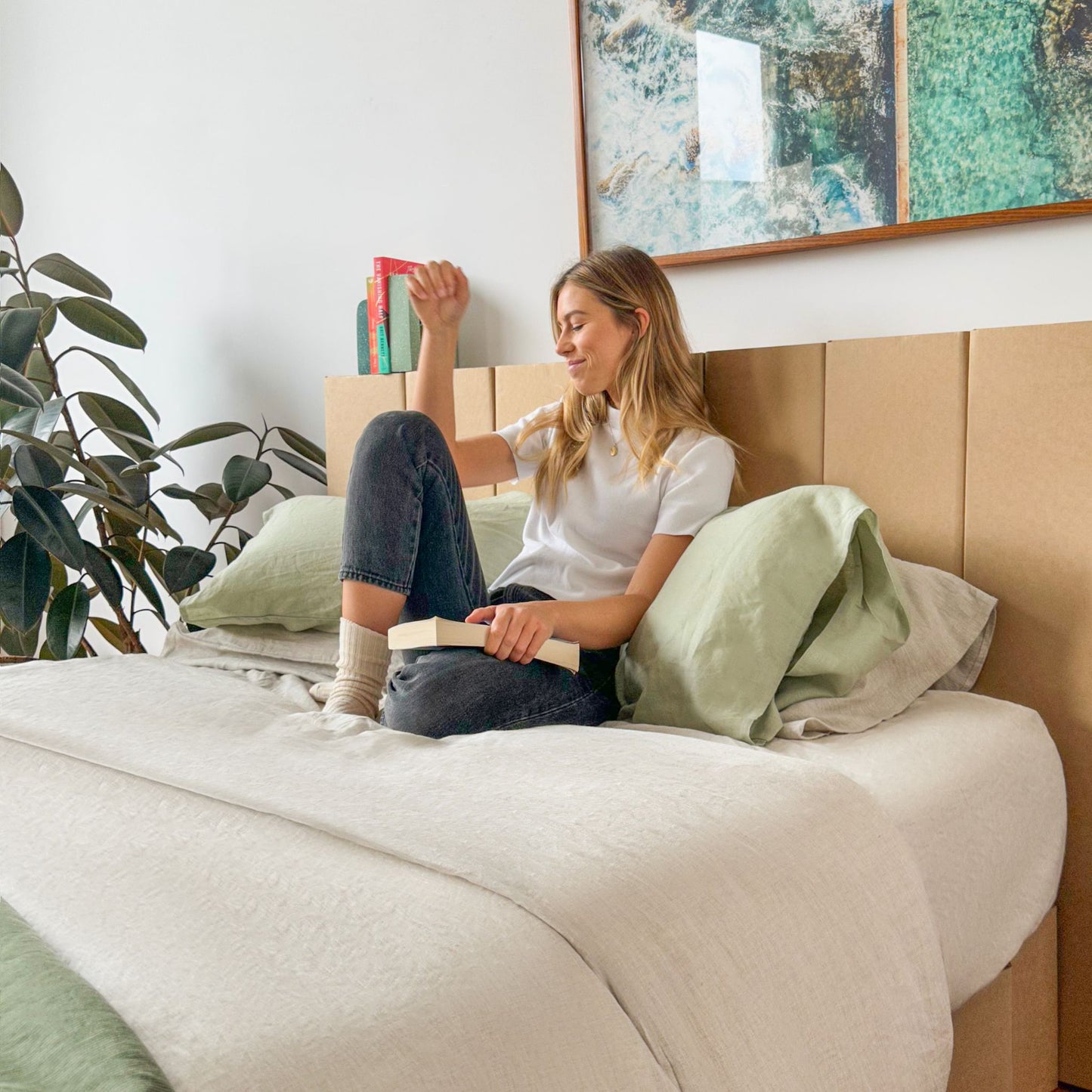 Woman sitting on the bed leaning on Yona headboard in natural finish