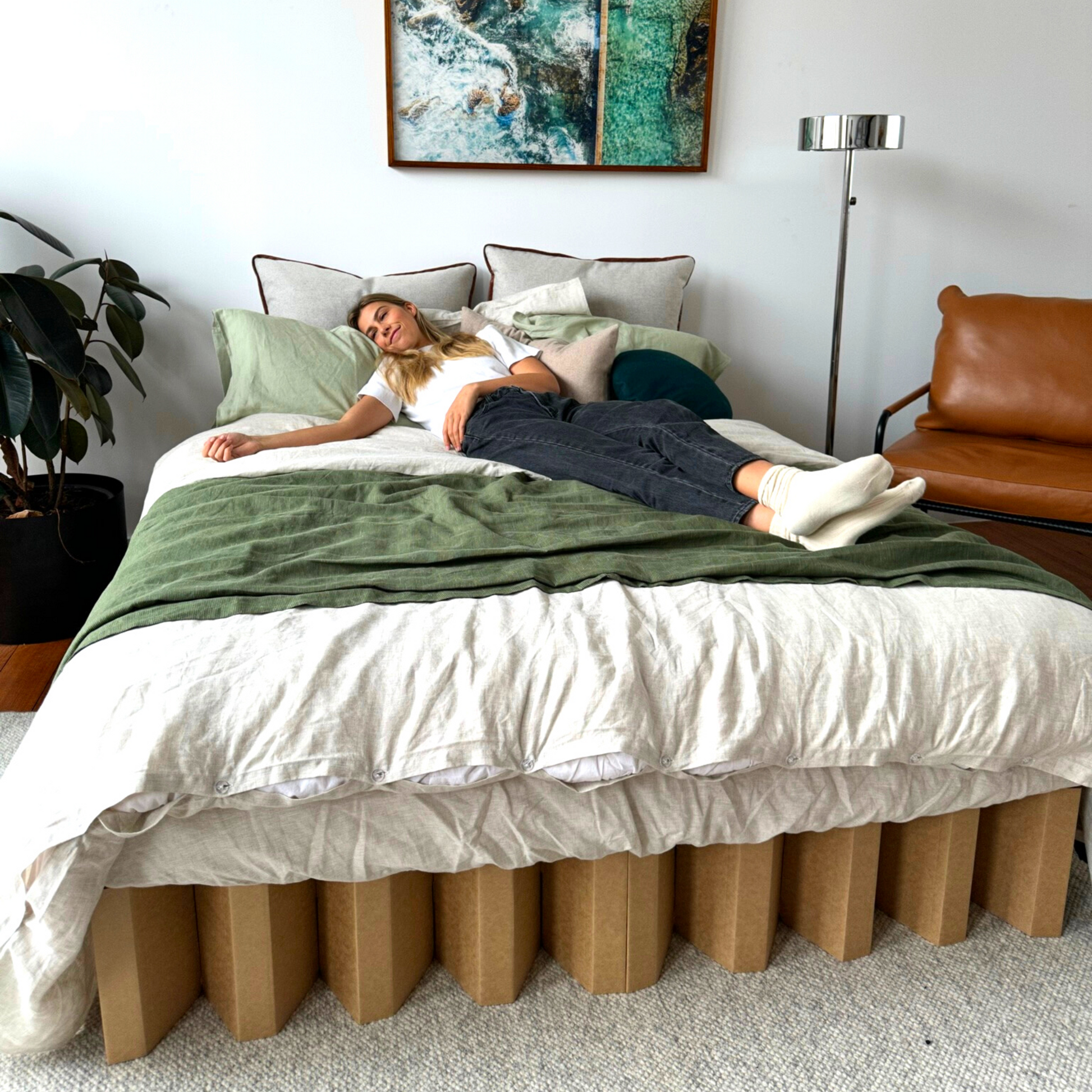 Yona Cardboard bed in natural finish lifestyle image with model lying on bed