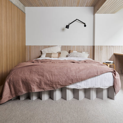 Yona Cardboard Bed in white finish with pink bedding in a modern wood-accented bedroom