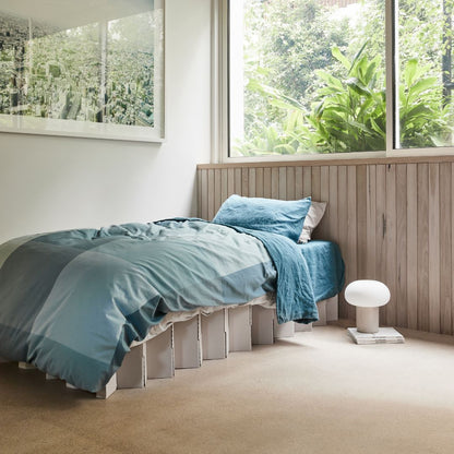 Yona Cardboard Bed in white finish styled as a single bed with blue bedding in a bright room